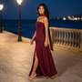 Mujer con vestido largo palabra de honor y fular paseando por un paseo marítimo de noche