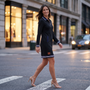 Vestido polo de mujer con media cremallera y bolsillos color negro, look urbano al atardecer con calle comercial iluminada