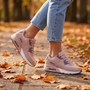 Mujer paseando por un parque en otoño con zapatillas deportivas con cámara de aire en rosa y púrpura